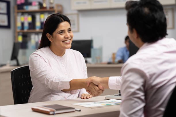 male client handshaking with bank teller at bank counter