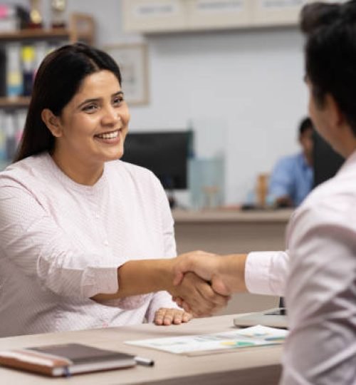 male client handshaking with bank teller at bank counter